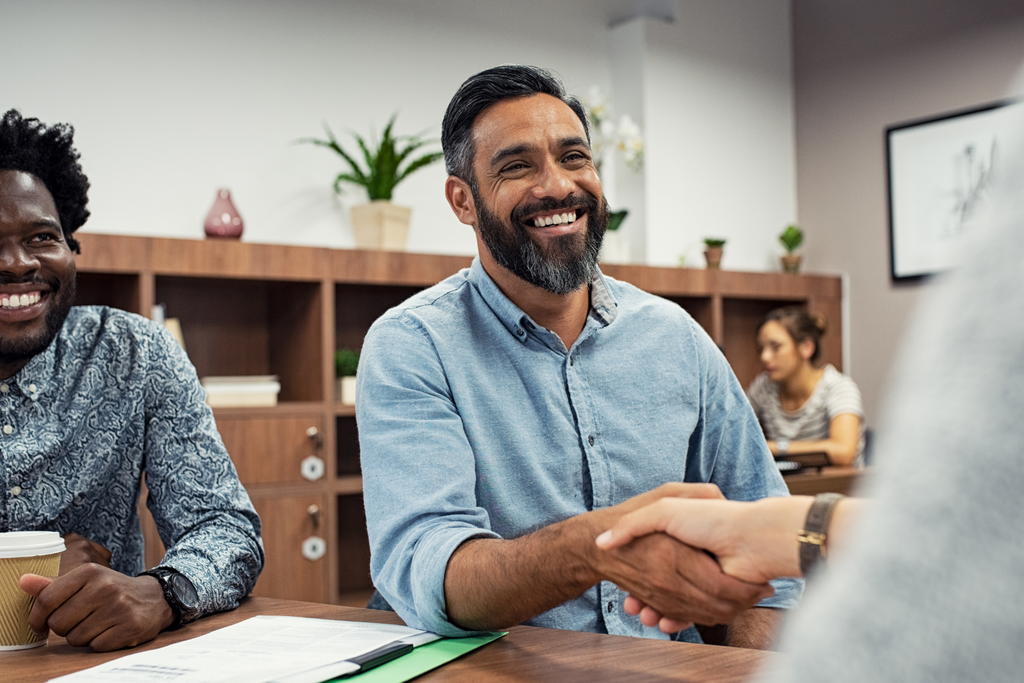 Two men sat at a table shaking hands