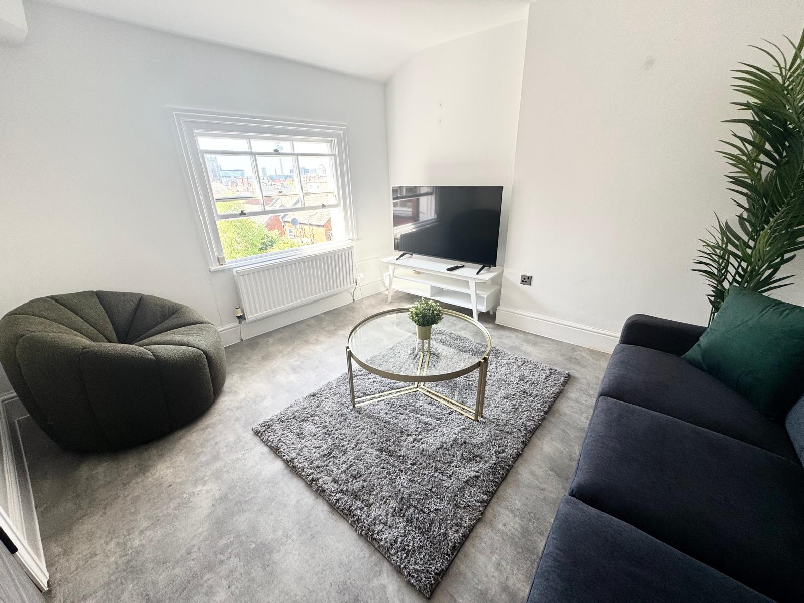 Bright and modern living room at Hope Street apartment with TV, glass coffee table, chair and sofa