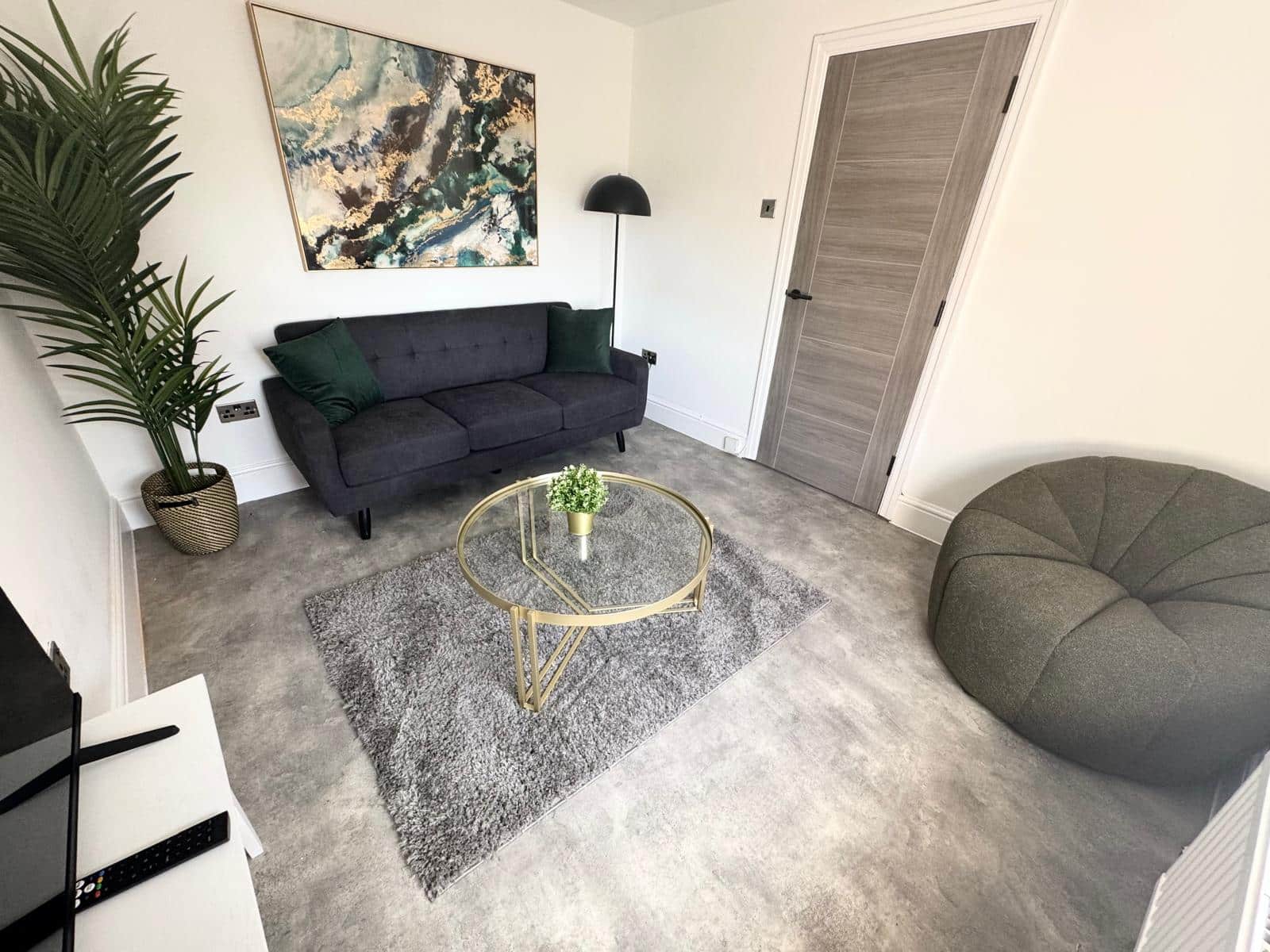 Newly refurbished living room at Hope Street apartment with sofa, glass coffee table, floor chair and big green plant
