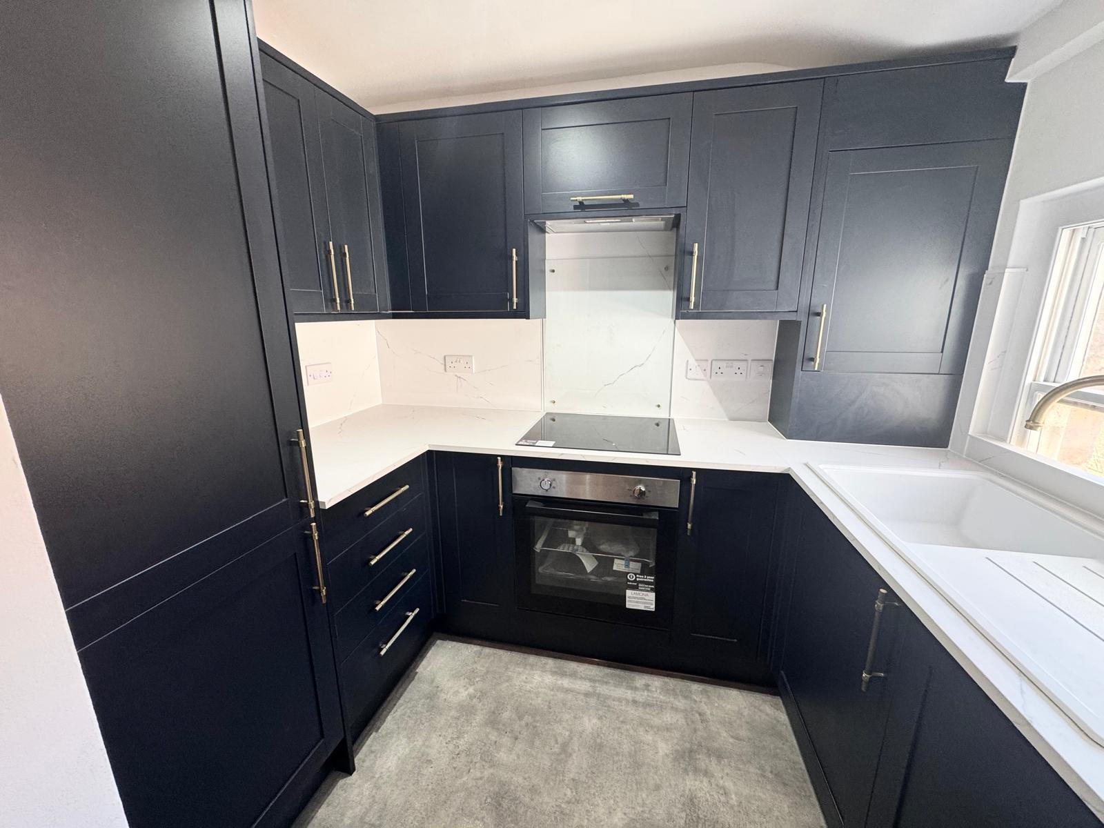 Modern, newly refurbished black kitchen with white counters