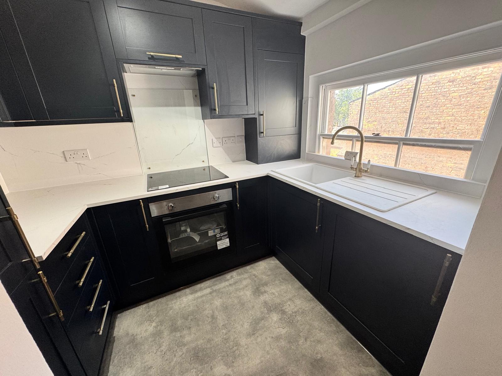 Modern, newly refurbished black kitchen with white counters
