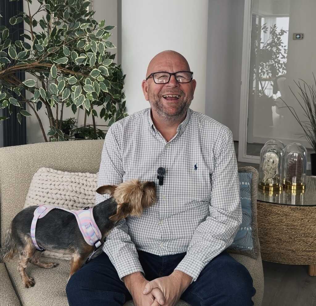 Wayne Walker, Leaseholder at Alexandra Tower sat on a sofa with his dog